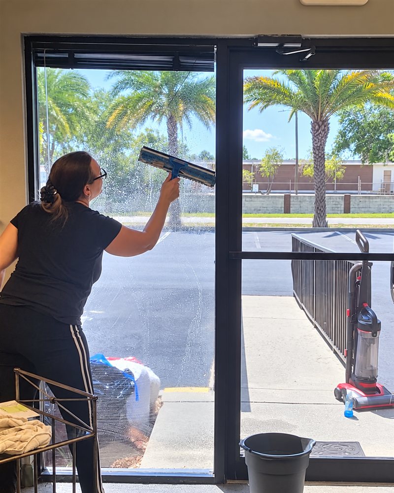 Nada's Cleaning team member cleaning a storefront window